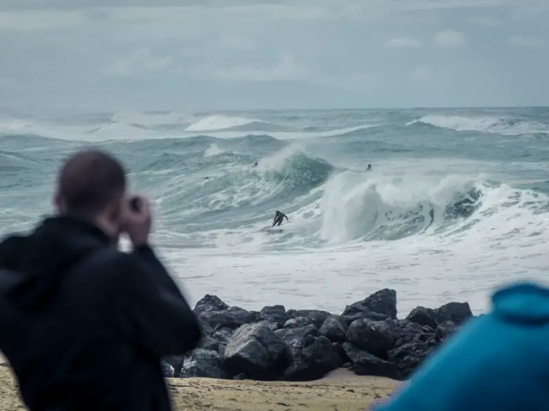 man photographing surfers from the beach