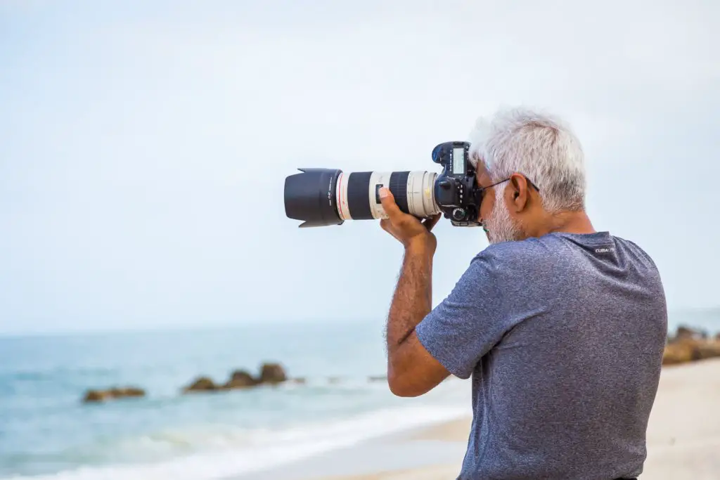 man shooting surfers from the beach with telephoto lens